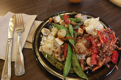 Hier sieht man einen Teller mit Essen. Es gibt Gemüse, Reis und Tofu.